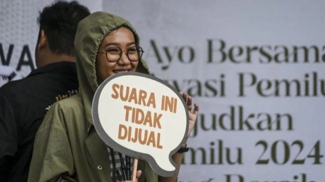 Warga menunjukkan tulisan penolakan politik uang saat Bawaslu On Car Free Day pada Hari Bebas Kendaraan Bermotor (HBKB) di depan gedung Bawaslu, Jakarta, Minggu (28/1/2024). (ANTARA FOTO/Hafidz Mubarak A)