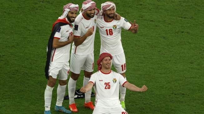 Para pemain Timnas Yordania memakai serban sebagai bentuk selebrasi usai memastikan tiket final Piala Asia 2023 di Qatar. [KARIM JAAFAR / AFP]