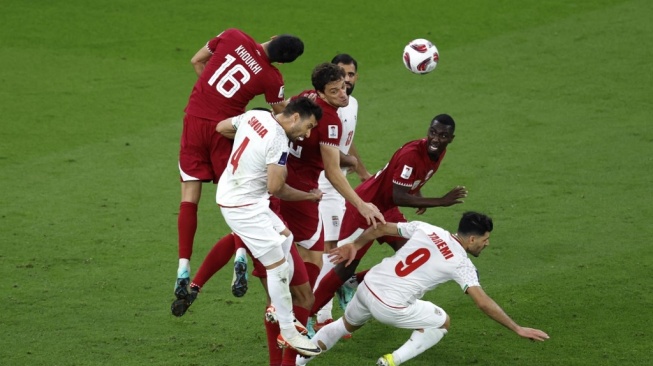 Bek Qatar Boualem Khoukhi menyundul bola melewati bek Iran Shojae Khalilzadeh dan penyerang Mehdi Taremi pada pertandingan sepak bola semifinal Piala Asia AFC Qatar 2023 antara Iran dan Qatar di Stadion al-Thumama di Doha pada 7 Februari 2024 .KARIM JAAFAR / AFP