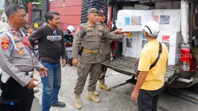 Sejumlah petugas membawa logistik Pemilu 2024 menuju tempat pemungutan suara di RW 02 Paseban, Jakarta, Selasa (13/2/2024). [Suara.com/Alfian Winanto]