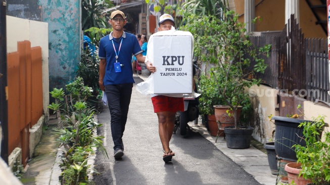 Sejumlah petugas membawa logistik Pemilu 2024 menuju tempat pemungutan suara di RW 02 Paseban, Jakarta, Selasa (13/2/2024). [Suara.com/Alfian Winanto]