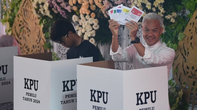 Calon presiden nomor urut 3 Ganjar Pranowo (kanan) menunjukkan surat suara didampingi anaknya Alam Ganjar (kiri) sebelum mencoblos di TPS 11 Lempongsari, Semarang, Jawa Tengah, Rabu (14/2/2024). [ANTARA FOTO/Akbar Nugroho Gumay].