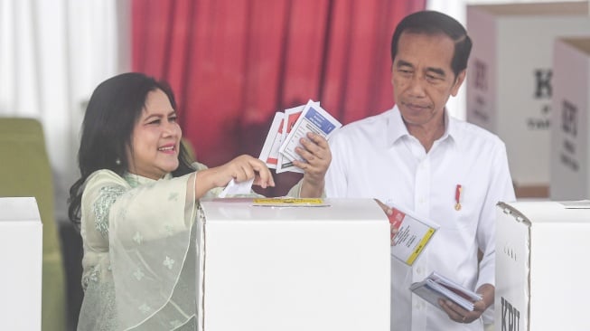 Presiden Joko Widodo (kanan) bersama Ibu Negara Iriana (kiri) memasukkan surat suara ke dalam kotak pada Pemilu 2024 di tempat pemungutan suara (TPS) 10 Kelurahan Gambir, kompleks Kantor Lembaga Administrasi Negara (LAN), Jakarta, Rabu (14/2/2024). [ANTARA FOTO/Muhammad Adimaja].