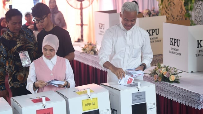 Calon presiden nomor urut 3 Ganjar Pranowo (kanan) bersama istri Siti Atikoh (kiri) dan anak Alam Ganjar (belakang) memasukkan surat suara ke dalam kotak suara usai mencoblos di TPS 11 Lempongsari, Semarang, Jawa Tengah, Rabu (14/2/2024). [ANTARA FOTO/Akbar Nugroho Gumay].