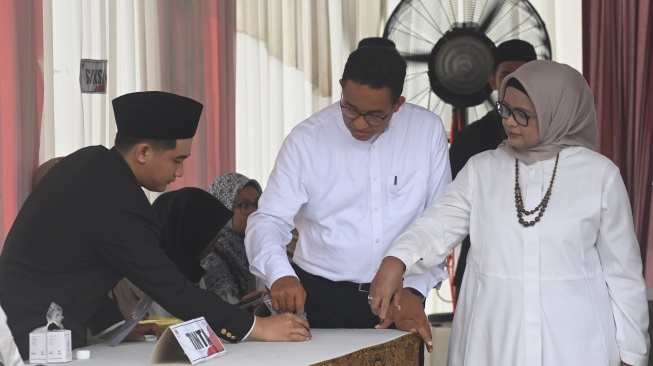 Capres nomor urut 1 Anies Baswedan (kedua kanan) bersama istrinya Fery Farhati (kanan) mencelupkan jari pada tinta usai mencoblos surat suara Pemilu 2024 di TPS 60, Lebak Bulus, Jakarta, Rabu (14/2/2024). [ANTARA FOTO/Indrianto Eko Suwarso].