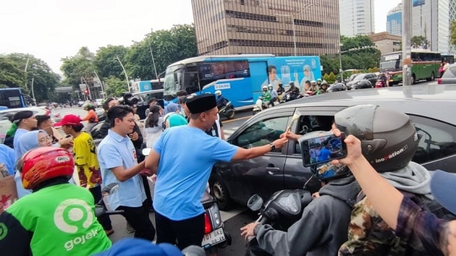 TKN Fanta Prabowo-Gibran membagikan bunga dan cokelat kepada masyarakat di kawasan Thamrin, Jakarta Pusat, Kamis (15/2/2024). [Dok. TKN Fanta]