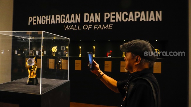 Pengunjung saat melihat Pameran Retrospektif 50 Tahun God Bless di Galeri Nasional, Jakarta, Jumat (16/2/2024). [Suara.com/Alfian Winanto]