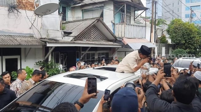 Capres nomor urut 2 Prabowo Subianto mencium anak kecil usai berziarah ke makam Habib Ali bin Abdurrahman Al-Habsyi alias Habib Ali Kwitang di Masjid Al-Riyadh, Kwitang, Jakarta Pusat, Jumat (16/2/2024) siang. (Suara.com/M. Yasir)