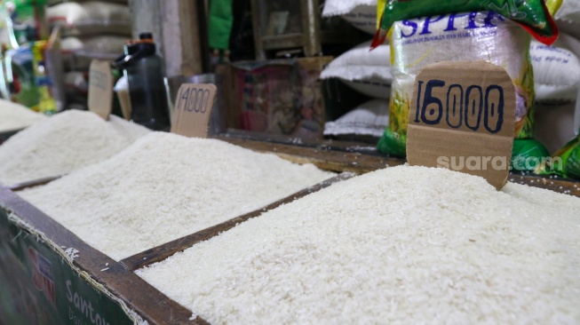 Pedagang beras melayani pembeli di pasar Cibubur, Jakarta, Senin (19/2/2024). [Suara.com/Alfian Winanto]