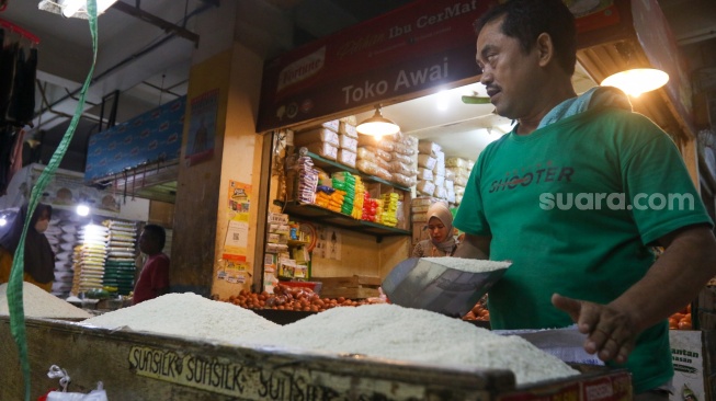 Pedagang beras melayani pembeli di pasar Cibubur, Jakarta, Senin (19/2/2024). [Suara.com/Alfian Winanto]