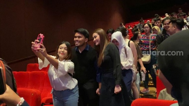 Seorang penonton meminta foto bareng dengan Thariq Halilintar dan Aaliyah Massaid di acara gala premier film Dealova di kawasan Kuningan, Jakarta Selatan, Rabu (21/2/2024). [Tiara Rosana/Suara.com]