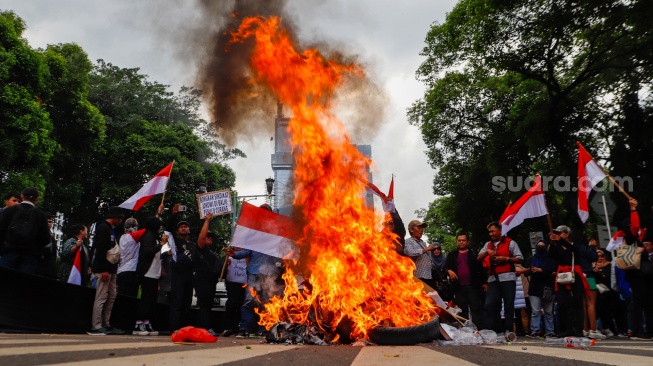 Massa yang tergabung dalam Gerakan Masyarakat Sipil Selamatkan Demokrasi Indonesia membakar ban saat menggelar aksi di depan Gedung Komisi Pemilihan Umum (KPU) RI, Jakarta, Jumat (23/2/2024). [Suara.com/Alfian Winanto]