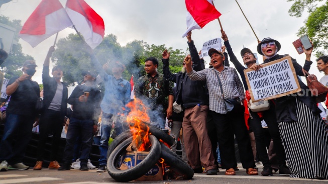 Massa yang tergabung dalam Gerakan Masyarakat Sipil Selamatkan Demokrasi Indonesia membakar ban saat menggelar aksi di depan Gedung Komisi Pemilihan Umum (KPU) RI, Jakarta, Jumat (23/2/2024). [Suara.com/Alfian Winanto]