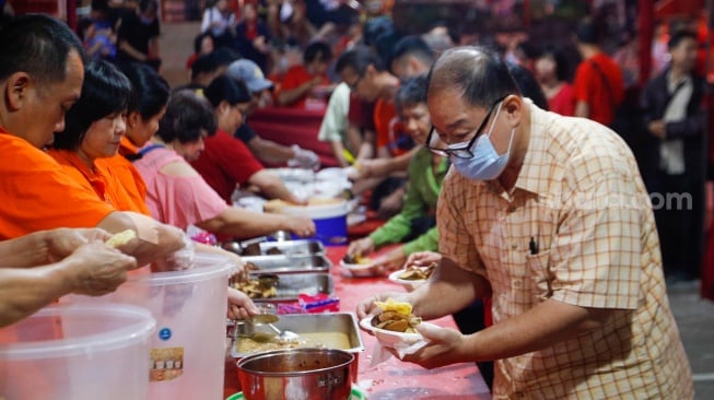 Warga keturunan Tionghoa mengambil makanan khas Lontong Cap Go Meh saat perayaan di Vihara Amurva Bhumi, Jakarta, Jumat (23/2/2024). [Suara.com/Alfian Winanto]