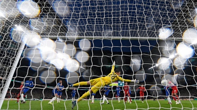 Bek Liverpool Virgil van Dijk (kiri) mencetak gol kemenangan melewati kiper Chelsea Djordje Petrovic saat pertandingan final Carabao Cup antara Chelsea dan Liverpool di stadion Wembley, London, Inggris, Minggu (25/2/2024). [Glyn KIRK / AFP]