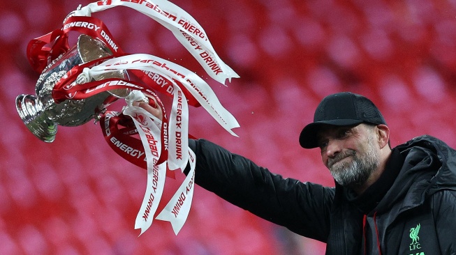 Manajer Liverpool Jurgen Klopp berselebrasi sambil mengangkat trofi setelah pertandingan final Carabao Cup antara Chelsea dan Liverpool di stadion Wembley, London, Inggris, Minggu (25/2/2024). [Adrian DENNIS/AFP]