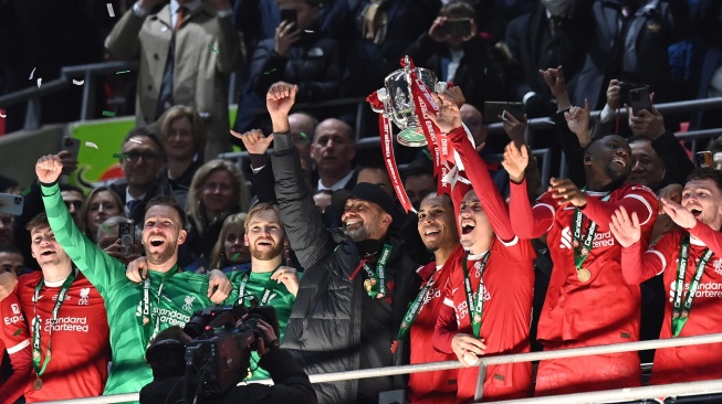 Manajer Liverpool asal Jerman Jurgen Klopp (tengah) bersama para pemain Liverpool mengangkat trofi setelah pertandingan final Carabao Cup antara Chelsea dan Liverpool di stadion Wembley, London, Inggris, Minggu (25/2/2024). [Glyn KIRK / AFP]