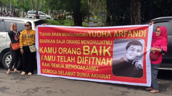 Keluarga tersangka Yudha Arfandi membawa spanduk ke lokasi rekonstruksi kematian Dante di kolam renang Tirtamas Water Park, Pondok Kelapa, Jakarta, Rabu (28/2/2024). [Pahami.id/Adiyoga Priyambodo]