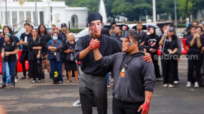 Sejumlah aktivis menampilkan aksi teaterikal dengan memakai topeng Presiden Joko Widodo dan Menhan Prabowo Subianto saat Aksi Kamisan ke-807 di seberang Istana Merdeka, Jakarta, Kamis (29/2/2024). [Suara.com/Alfian Winanto]
