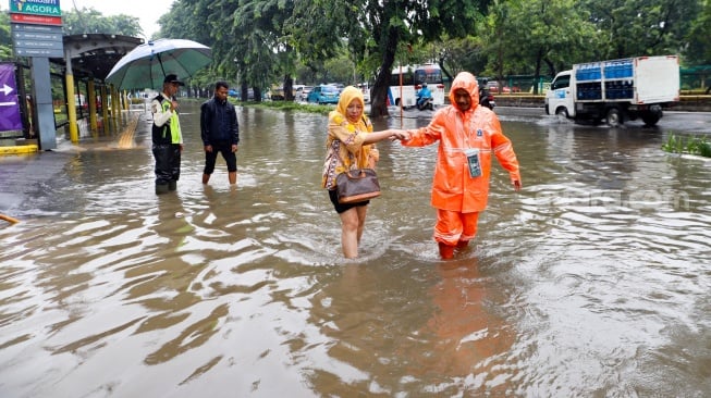 Warga berjalan melewati banjir di sekitar Cempaka Putih, Jakarta, Kamis (29/2/2024). [Suara.com/Alfian Winanto]