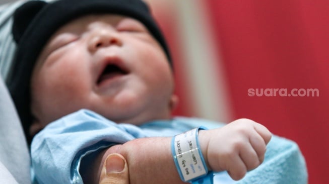 Tenaga kesehatan memasangkan gelang identitas untuk bayi yang baru lahir di RSUD Kramat Jati, Jakarta, Kamis (29/2/2024). [Suara.com/Alfian Winanto]
