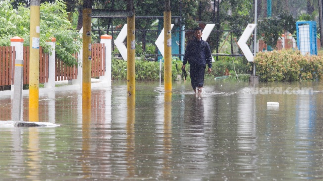 Warga berjalan melewati banjir di sekitar Cempaka Putih, Jakarta, Kamis (29/2/2024). [Suara.com/Alfian Winanto]