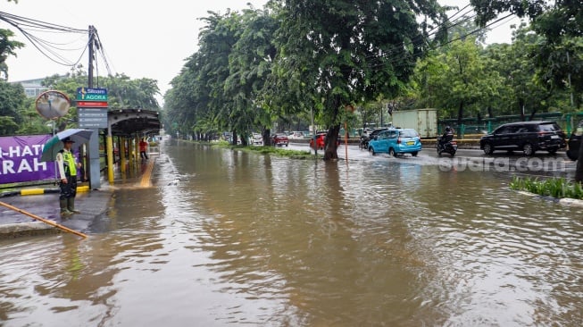 Warga berjalan melewati banjir di sekitar Cempaka Putih, Jakarta, Kamis (29/2/2024). [Suara.com/Alfian Winanto]