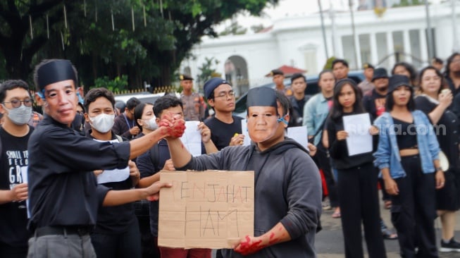 Sejumlah aktivis menampilkan aksi teaterikal dengan memakai topeng Presiden Joko Widodo dan Menhan Prabowo Subianto saat Aksi Kamisan ke-807 di seberang Istana Merdeka, Jakarta, Kamis (29/2/2024). [Suara.com/Alfian Winanto]