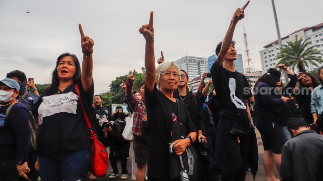 Penggerak Aksi Kamisan, Maria Catarina Sumarsih (tengah) bersama sejumlah aktivis, akademisi, mahasiswa, dan elemen masyarakat sipil menunjuk ke arah istana Ssaat mengikuti Aksi Kamisan ke-807 di seberang Istana Merdeka, Jakarta, Kamis (22/2/2024). [Suara.com/Alfian Winanto]
