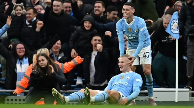 Penyerang Manchester City, Erling Haaland (bawah) merayakan gol bersama gelandang serang Phil Foden pada laga Liga Inggris kontra Manchester United di Stadion Etihad, Manchester, yang rampung Senin (4/3/2024) dini hari WIB. [PAUL ELLIS / AFP]