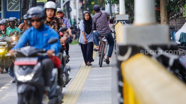 Pengendara sepeda motor melintas di trotoar kawasan Matraman, Jakarta, Selasa (5/3/2024). [Suara.com/Alfian Winanto]