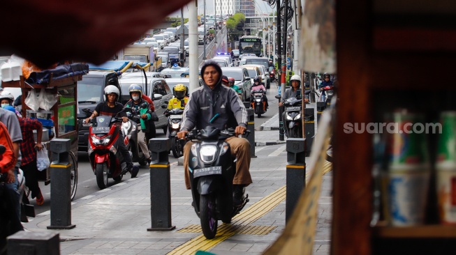 Pengendara sepeda motor melintas di trotoar kawasan Matraman, Jakarta, Selasa (5/3/2024). [Suara.com/Alfian Winanto]