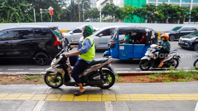 Pengendara sepeda motor melintas di trotoar kawasan Matraman, Jakarta, Selasa (5/3/2024). [Suara.com/Alfian Winanto]