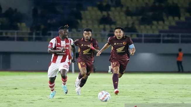 Pemain nomor punggung 25 Persis Solo, Moussa Sidibe (kostum merah putih) saat membawa bola dan dikawal dua pemain PSM Makassar dalam pertandingan Liga 1 2024, di Stadion Manahan Solo, Senin (4/3/2024) malam, ANTARA/Bambang Dwi Marwoto.