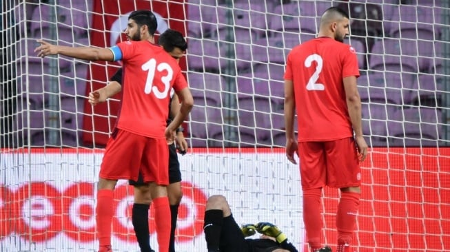 Penjaga gawang Mouez Tunisia Mouez Hassen (tengah) berbaring di samping gelandang Tunisia Ferjani Sassi (kiri) dan bek Tunisia Syam Ben Youssef selama pertandingan persahabatan antara Tunisia vs Turki di stadion Stade de Geneve di Jenewa pada 1 Juni 2018. Kata Maaloul Ia sempat meminta kipernya, Mouez Hassen, untuk melakukan simulasi cedera pada dua laga pramusim pertama Piala Dunia 2018 agar para pemainnya bisa berbuka puasa Ramadhan.Fabrik COFFRINI / AFP.