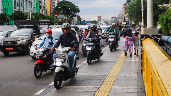 Pengendara sepeda motor melintas di trotoar kawasan Matraman, Jakarta, Selasa (5/3/2024). [Suara.com/Alfian Winanto]