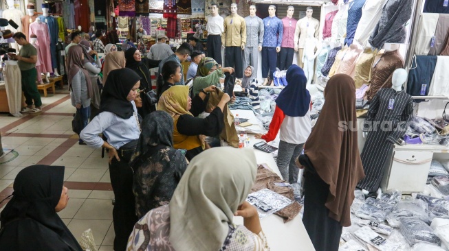 Pengunjung memilih pakaian di Pasar Tanah Abang, Jakarta, Kamis (7/3/2024). [Suara.com/Alfian Winanto]
