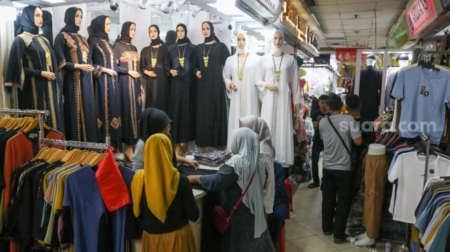 Pengunjung memilih pakaian di Pasar Tanah Abang, Jakarta, Kamis (7/3/2024). [Suara.com/Alfian Winanto]
