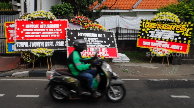 Pengendara melintas didepan karangan bunga menolak kecurangan pemilu di depan Kantor DPP PDI Perjuangan di Jakarta, Jumat (8/3/2024). [Suara.com/Alfian Winanto]