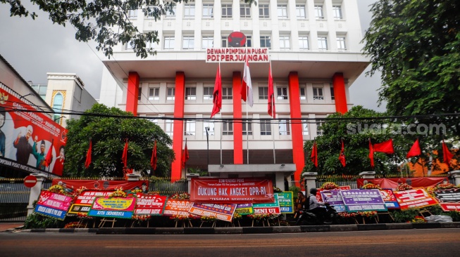 Pengendara melintas didepan karangan bunga menolak kecurangan pemilu di depan Kantor DPP PDI Perjuangan di Jakarta, Jumat (8/3/2024). [Suara.com/Alfian Winanto]