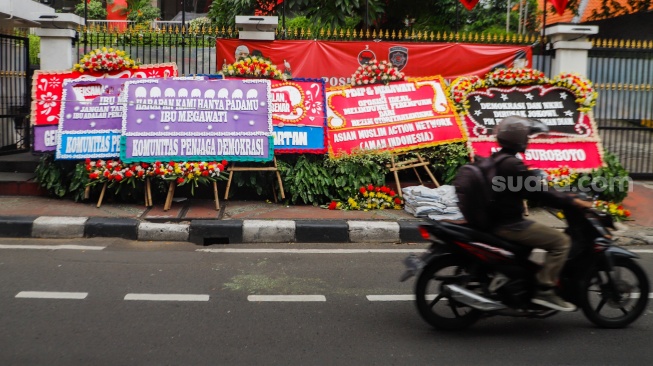 Pengendara melintas didepan karangan bunga menolak kecurangan pemilu di depan Kantor DPP PDI Perjuangan di Jakarta, Jumat (8/3/2024). [Suara.com/Alfian Winanto]