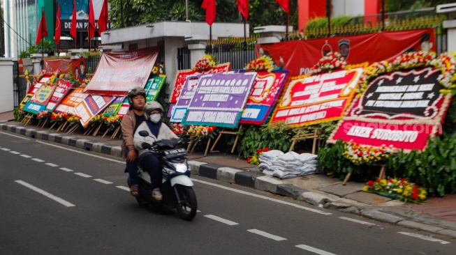 Pengendara melintas didepan karangan bunga menolak kecurangan pemilu di depan Kantor DPP PDI Perjuangan di Jakarta, Jumat (8/3/2024). [Suara.com/Alfian Winanto]