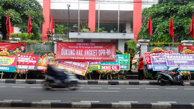 Pengendara melintas didepan karangan bunga menolak kecurangan pemilu di depan Kantor DPP PDI Perjuangan di Jakarta, Jumat (8/3/2024). [Suara.com/Alfian Winanto]