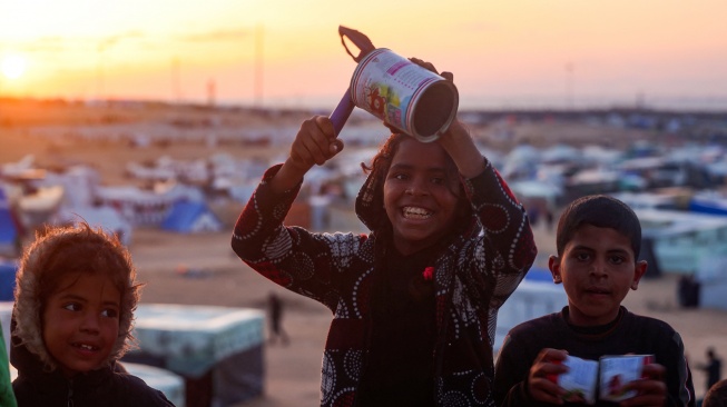 Anak-anak bermain di kamp pengungsi Palestina di Rafah, di Jalur Gaza selatan, pada malam bulan suci Ramadhan pada 10 Maret 2024, di tengah pertempuran yang sedang berlangsung antara Israel dan kelompok militan Hamas. [MOHAMMED ABED / AFP]