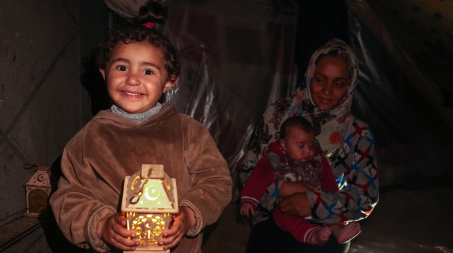 Anak-anak Palestina bermain dengan lentera tradisional "fanous" menyambut dimulainya bulan suci Ramadhan, di kota Rafah, Jalur Gaza selatan, Palestina, Minggu (10/3/2024). [SAID KHATIB/AFP]
