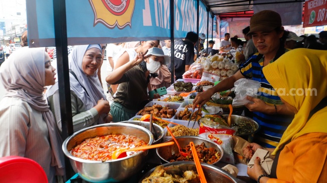 Pedagang melayani pembeli makanan di Pasar Takjil Bendungan Hilir, Jakarta, Rabu (13/3/2024). [Suara.com/Alfian Winanto]