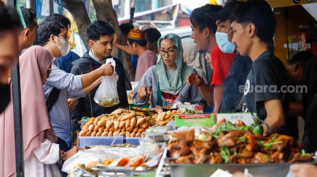 Pedagang melayani pembeli makanan di Pasar Takjil Bendungan Hilir, Jakarta, Rabu (13/3/2024). [Suara.com/Alfian Winanto]