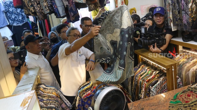 Menteri Perdagangan (Mendag) Zulkifli Hasan memilih pakaian saat melakukan kunjungan di Blok A Pasar Tanah Abang, Jakarta, Kamis (14/3/2024). [Suara.com/Alfian Winanto]