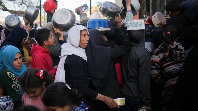 Pengungsi Palestina mengumpulkan makanan yang disumbangkan oleh sebuah badan amal untuk berbuka puasa di Rafah, Jalur Gaza Selatan, Senin (11/3/2024). [AFP]