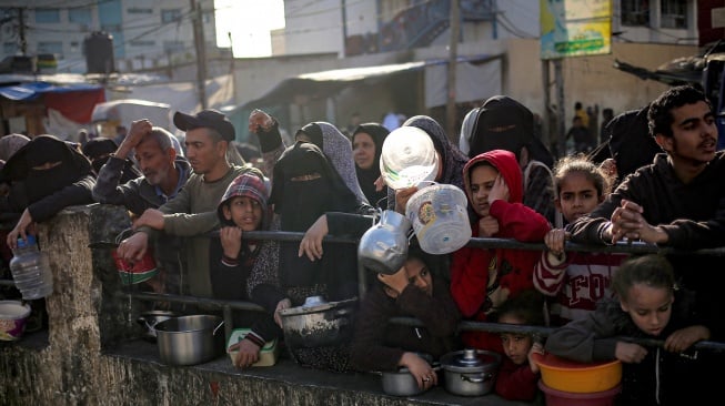 Pengungsi Palestina mengumpulkan makanan yang disumbangkan oleh sebuah badan amal untuk berbuka puasa di Rafah, Jalur Gaza Selatan, Senin (11/3/2024). [AFP]